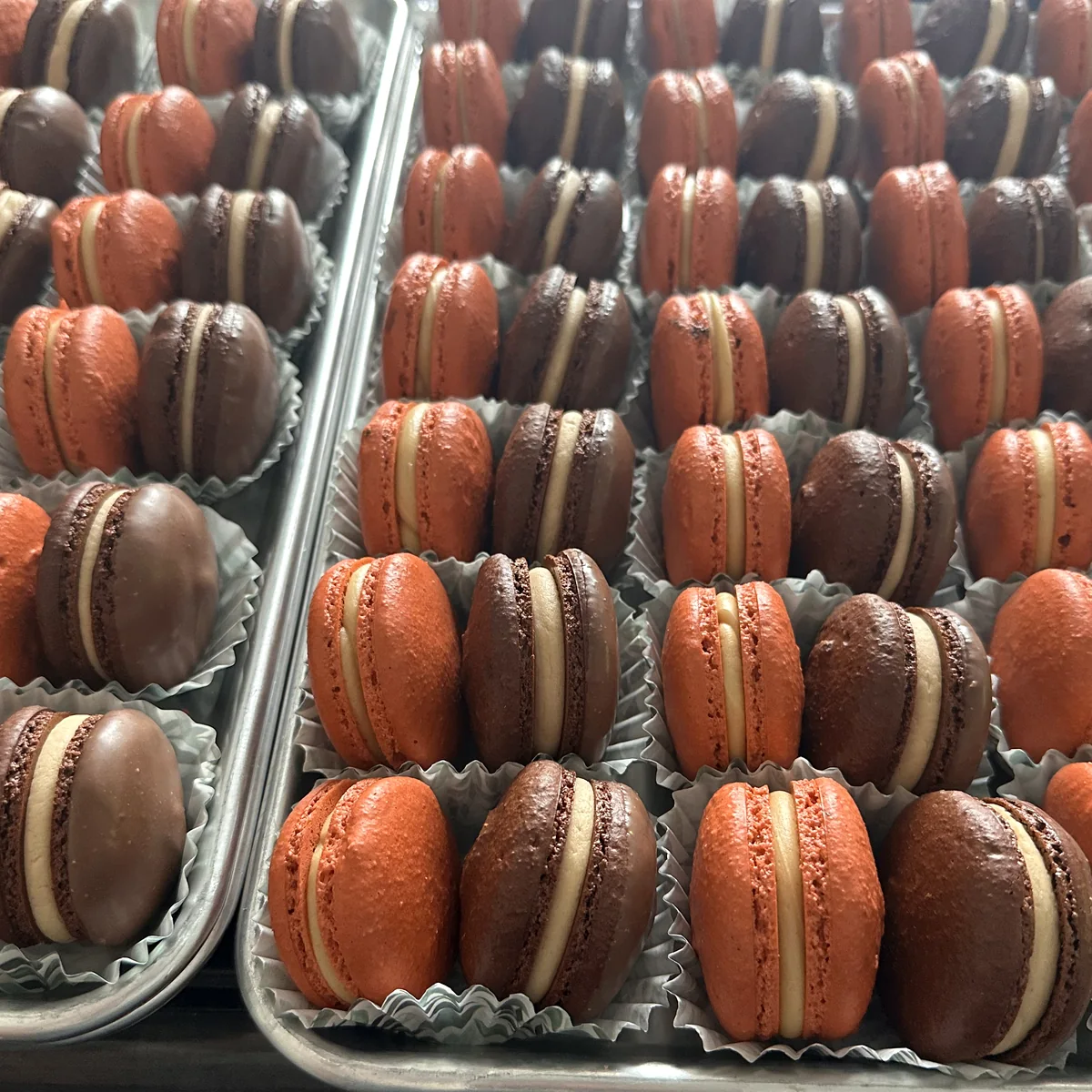Trays of red and chocolate macarons prepared for a large order